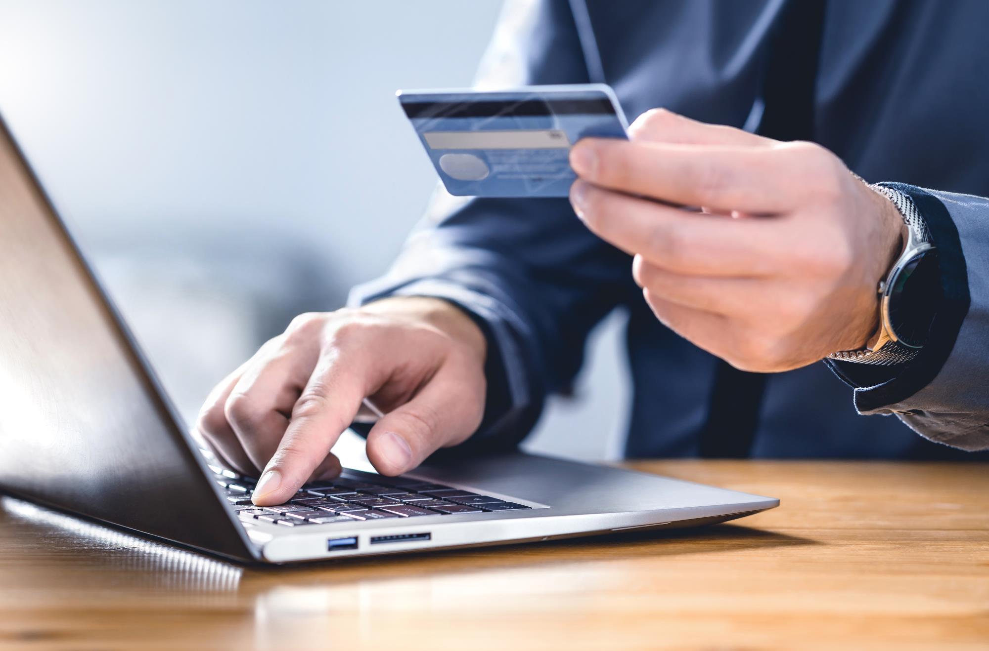 Person entering card information on laptop