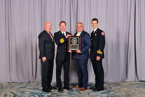 4 people standing while holding a plaque