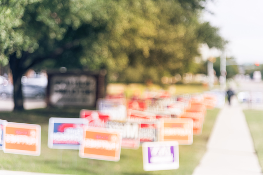 A blurry photo of election signs lining a street.